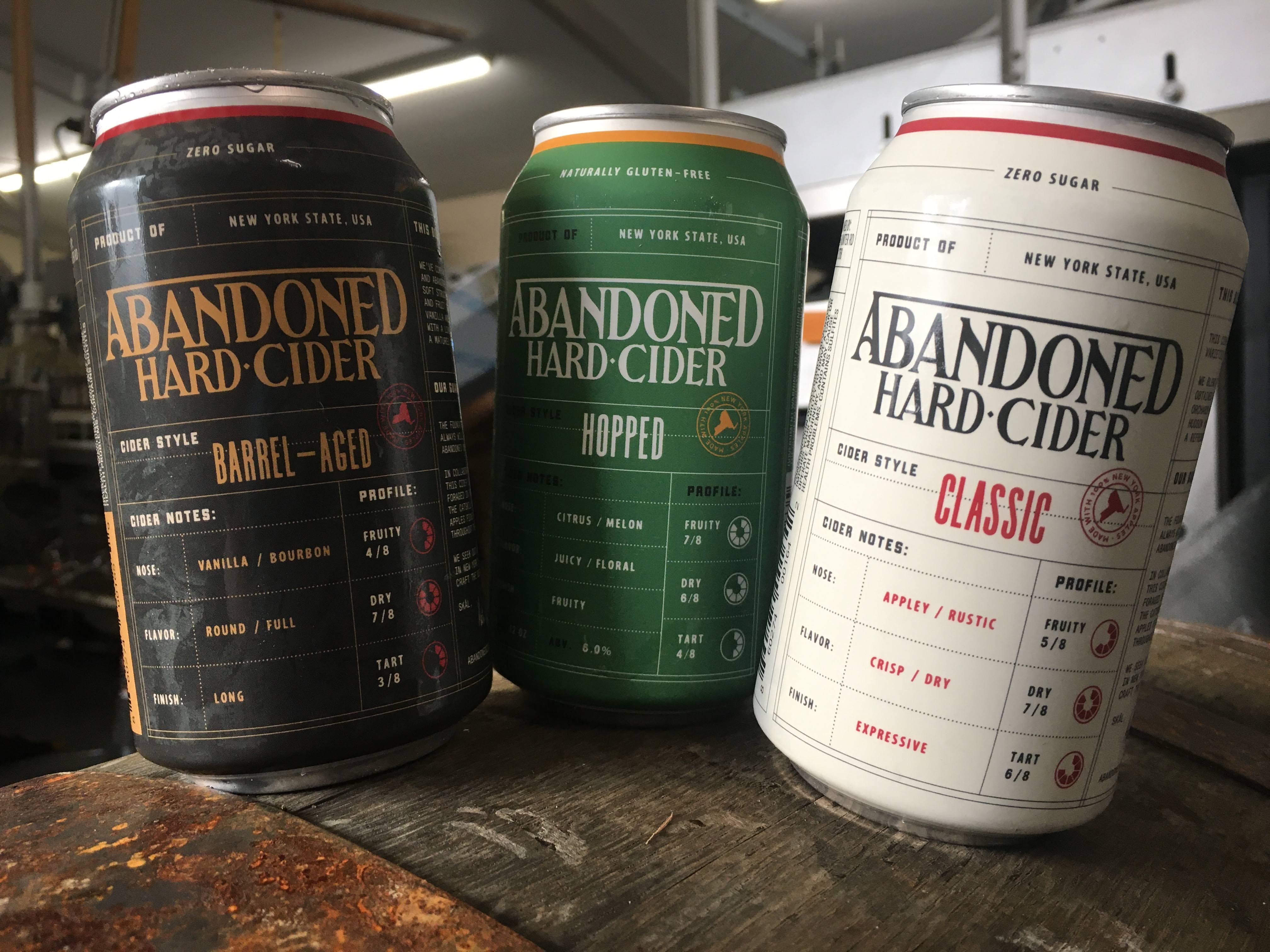Three Abandoned Hard Cider cans showcasing different flavors.